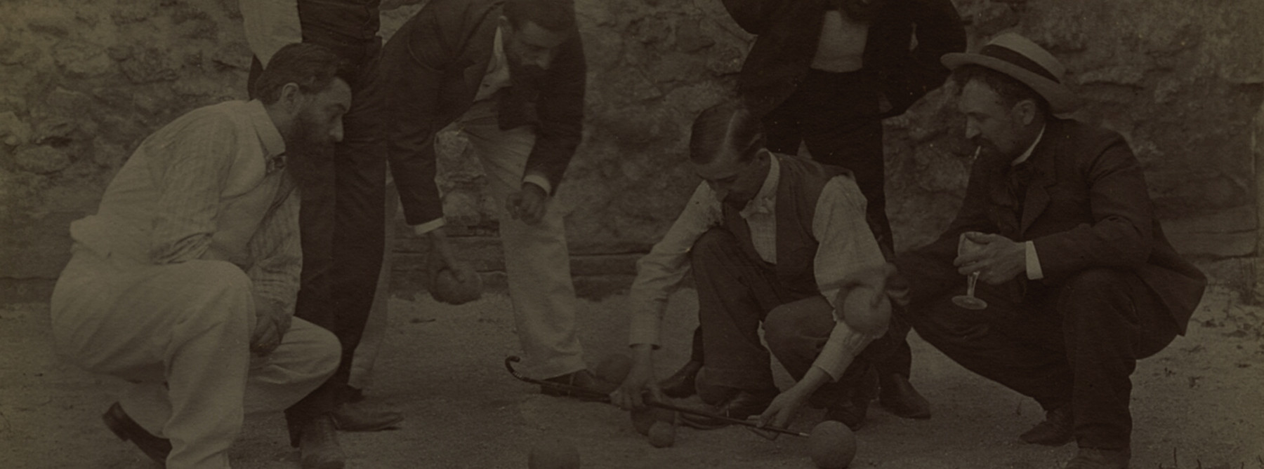 Marius qui joue aux boules avec ses amis , un verre à la main.