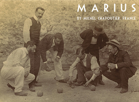 Marius jouant aux boules, un verre de vin à la main.