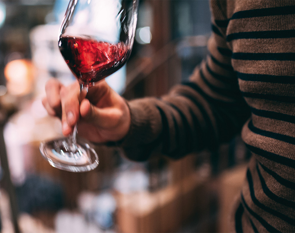 A hand rotating a glass of red wine.